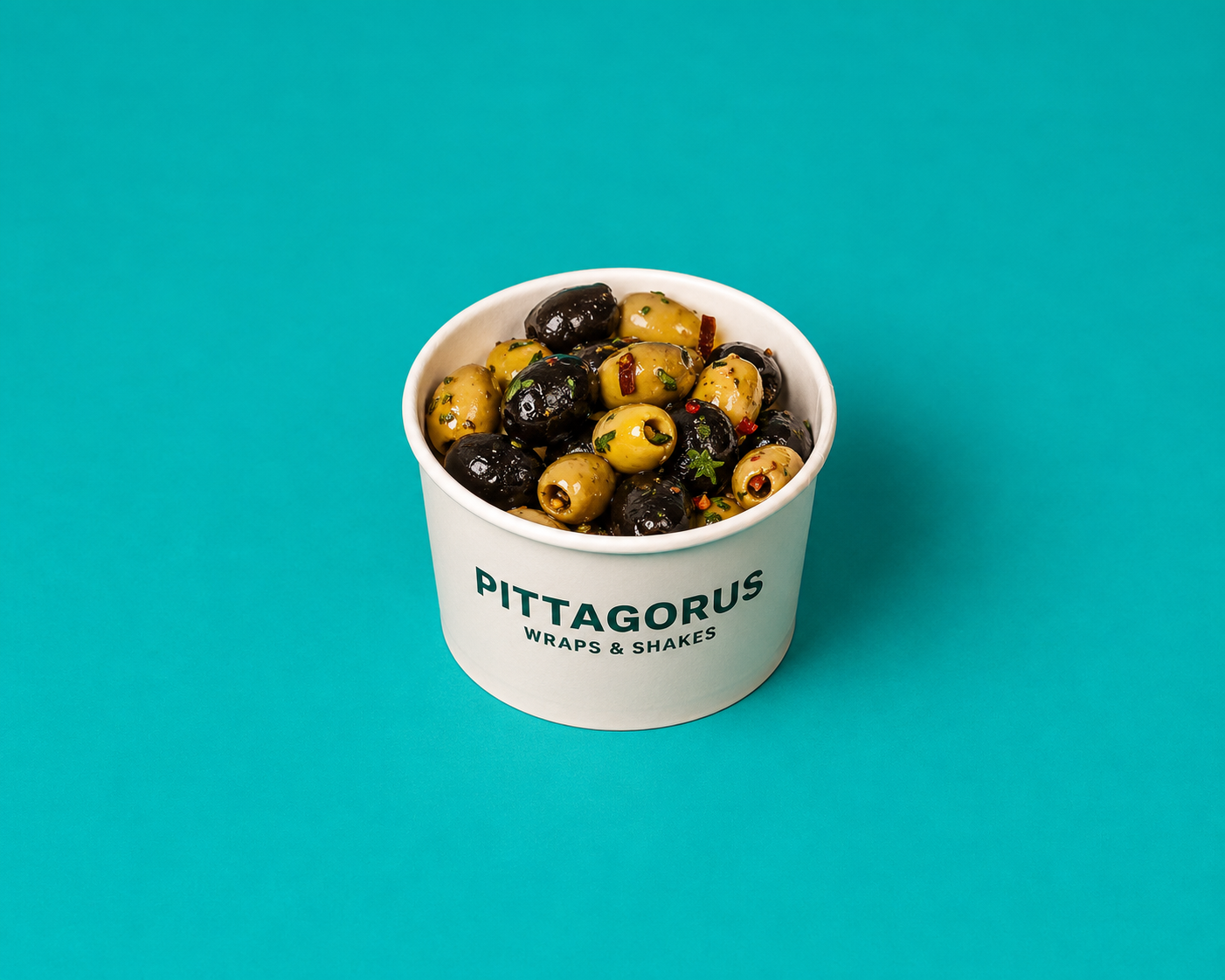 Tub of mixed green and black olives in herby brine