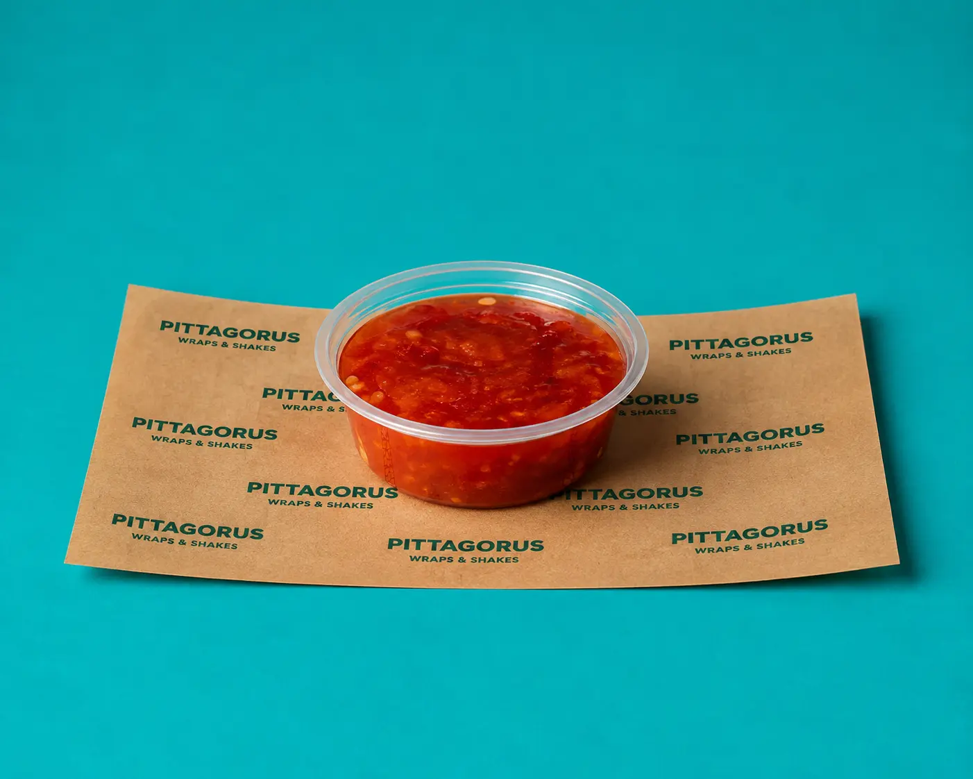 Tub of red chilli dip on Pittagorus paper